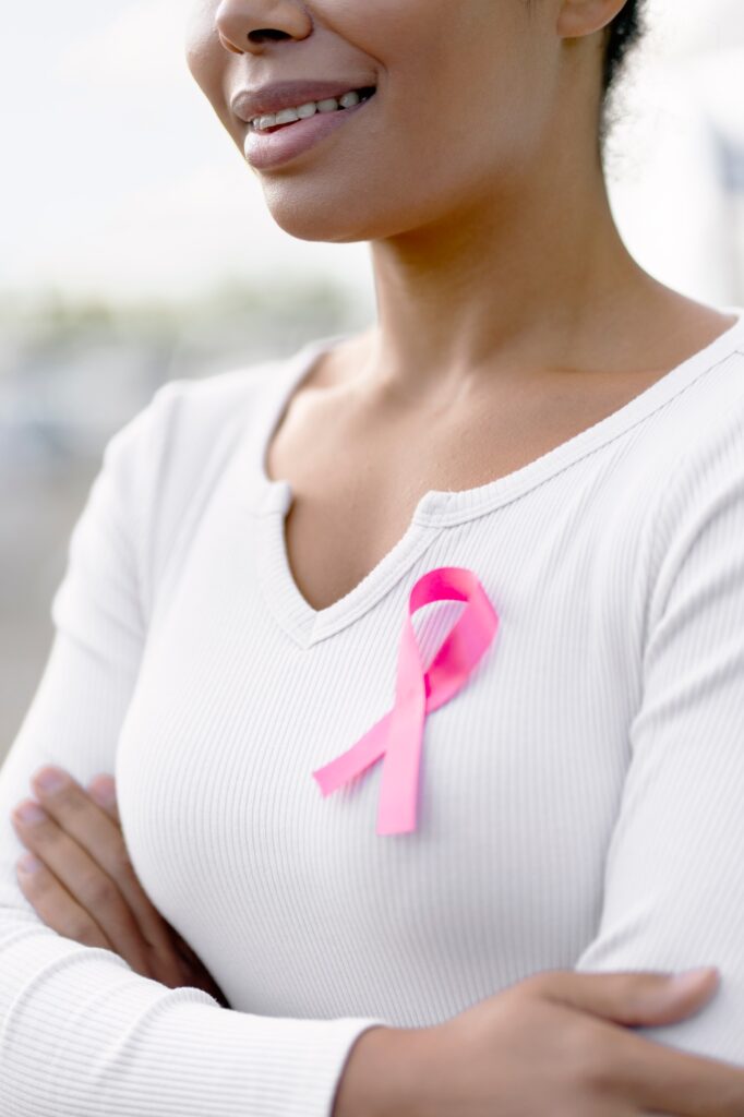 Woman smiling wearing pink ribbon supporting breast cancer awareness month